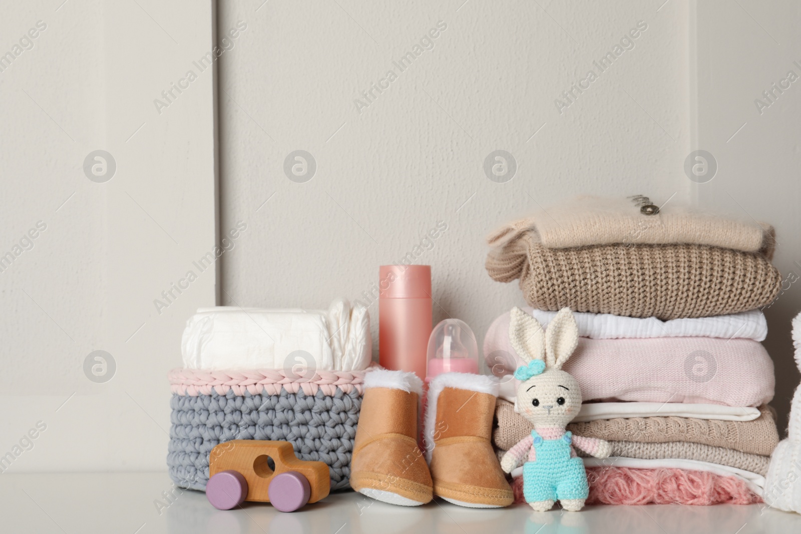 Photo of Baby clothes, toys and accessories on white table