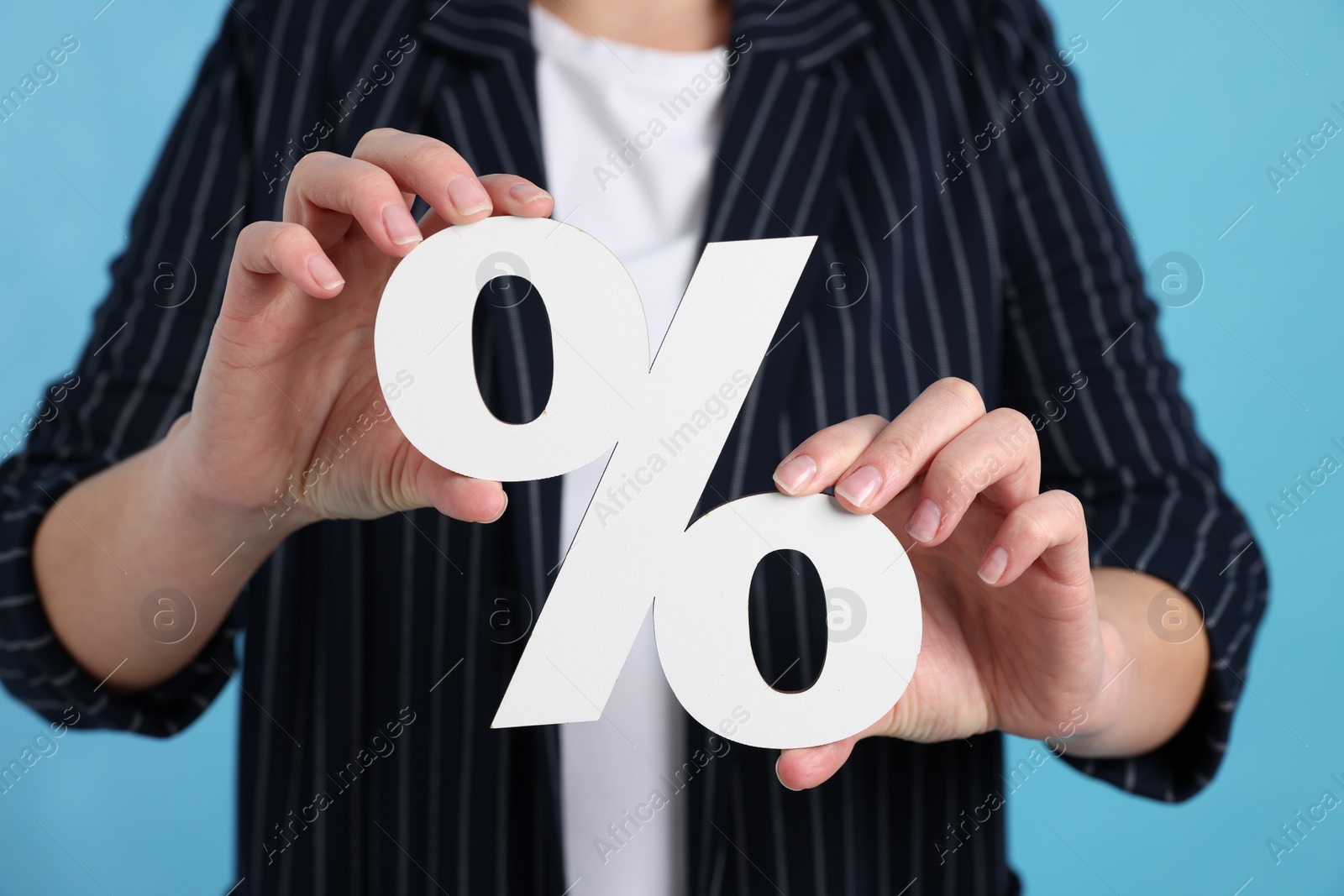 Photo of Woman holding percent sign on light blue background, closeup