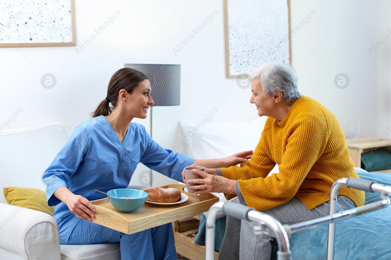 Photo of Care worker serving dinner for elderly woman in geriatric hospice