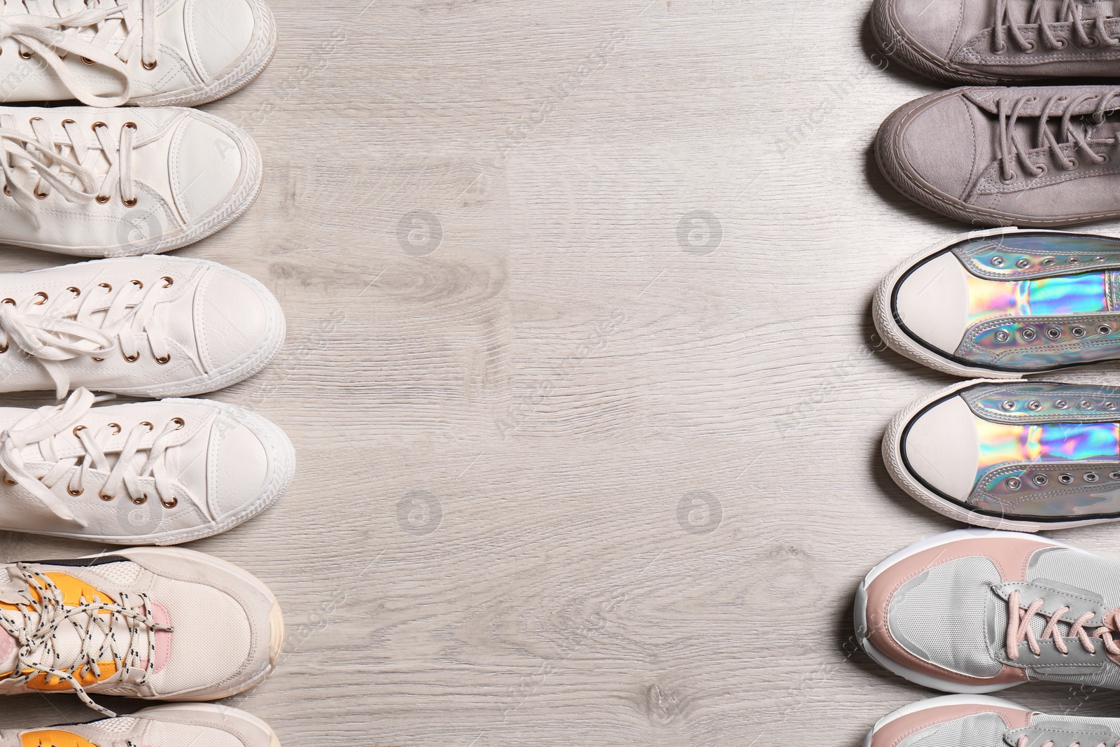 Photo of Different sneakers on wooden floor, flat lay. Space for text