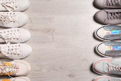 Photo of Different sneakers on wooden floor, flat lay. Space for text