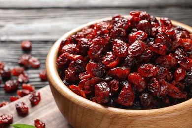 Photo of Bowl with cranberries on wooden table, closeup. Dried fruit as healthy snack