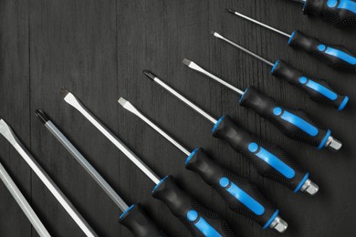 Photo of Set of screwdrivers on black wooden table, top view