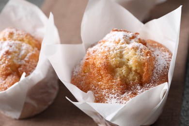 Photo of Delicious muffins with powdered sugar on table, closeup