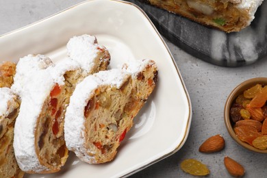 Photo of Traditional Christmas Stollen with icing sugar on grey table, flat lay
