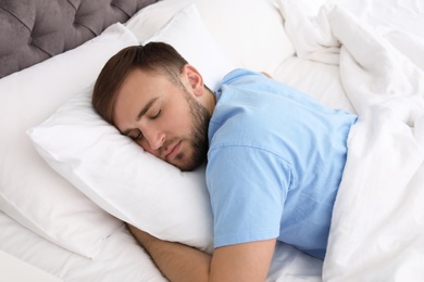 Photo of Young handsome man sleeping in bed at home. Early morning