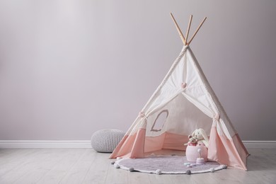 Photo of Cute child room interior with play tent near light grey wall, space for text