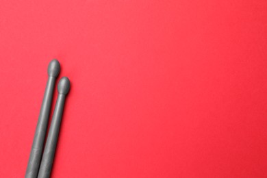 Photo of Two gray drum sticks on red background, top view. Space for text