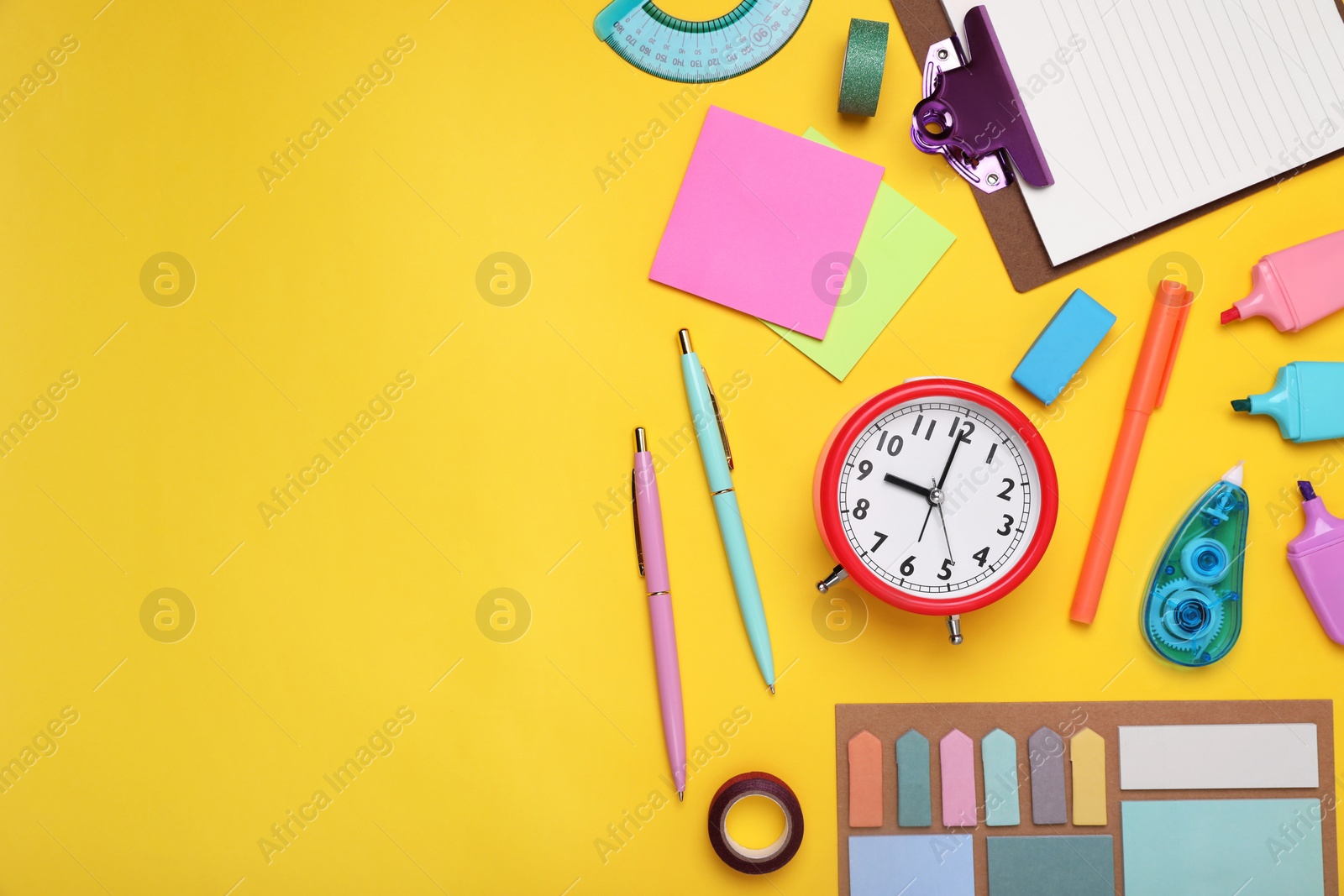 Photo of Flat lay composition with different school stationery and alarm clock on yellow background, space for text. Back to school