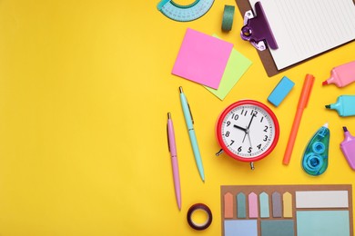 Photo of Flat lay composition with different school stationery and alarm clock on yellow background, space for text. Back to school