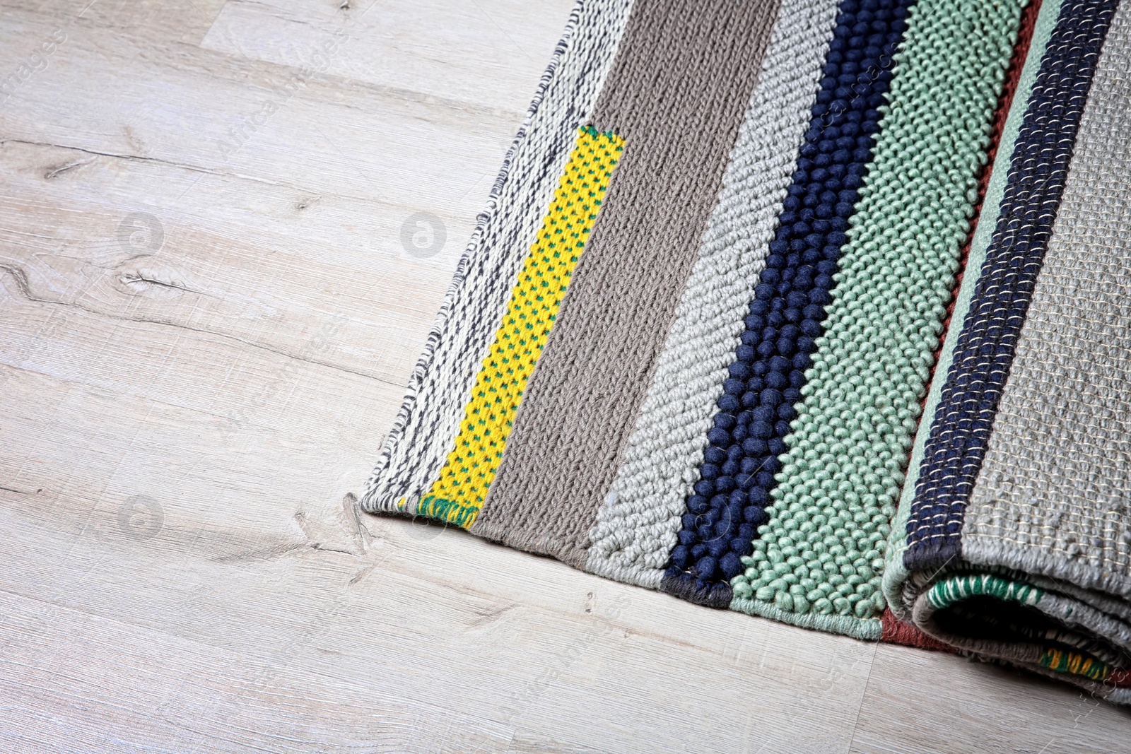 Photo of Colorful striped carpet on wooden floor