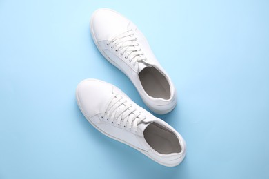 Photo of Pair of stylish white sneakers on light blue background, top view