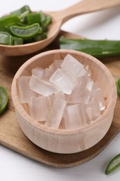 Photo of Aloe vera gel and slices of plant on white table, closeup