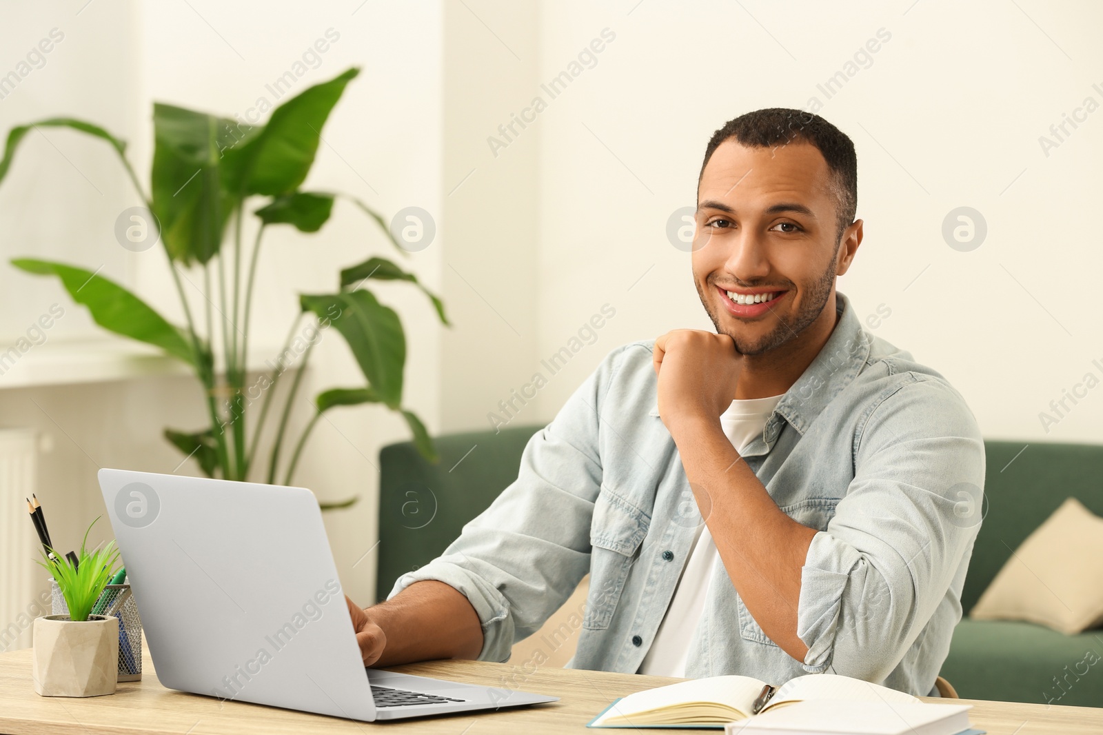 Photo of Portrait of African American man near laptop at wooden table in room