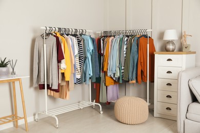 Photo of Racks with stylish clothes in cozy room interior. Fast fashion