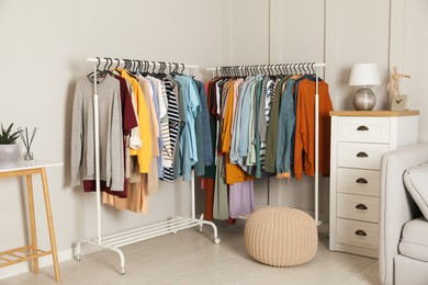 Racks with stylish clothes in cozy room interior. Fast fashion