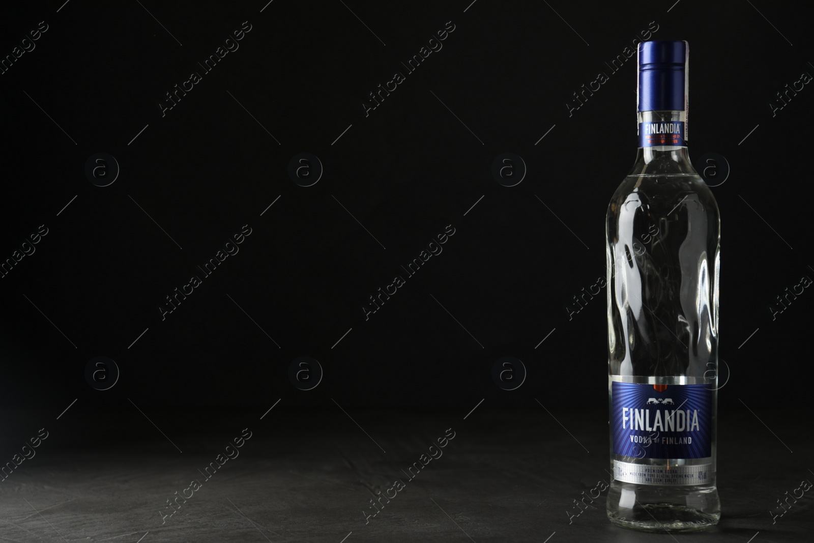 Photo of MYKOLAIV, UKRAINE - OCTOBER 03, 2019: Bottle of Finlandia vodka on grey table against black background. Space for text