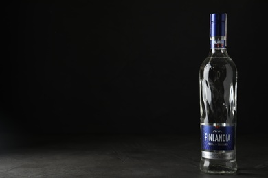 Photo of MYKOLAIV, UKRAINE - OCTOBER 03, 2019: Bottle of Finlandia vodka on grey table against black background. Space for text