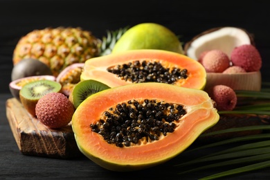 Photo of Fresh ripe papaya and other fruits on dark wooden table