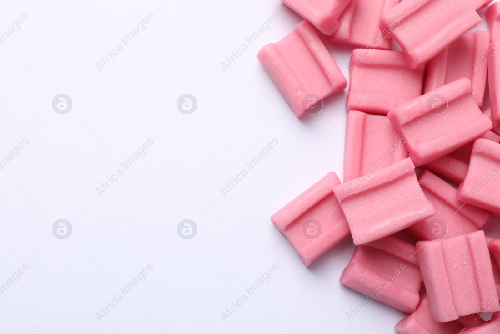 Photo of Tasty pink chewing gums on white background, flat lay. Space for text