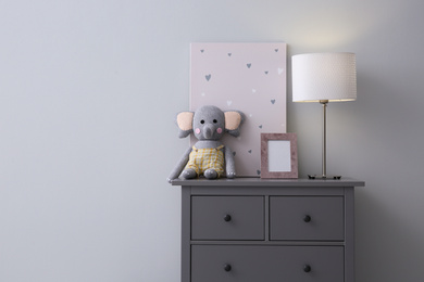 Modern grey chest of drawers near light wall in child room, space for text. Interior design