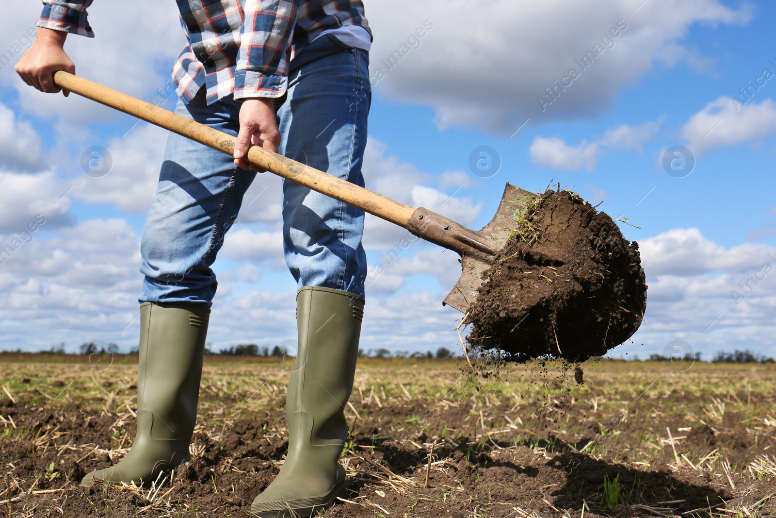 Photo of Man digging soil with shovel in field, closeup