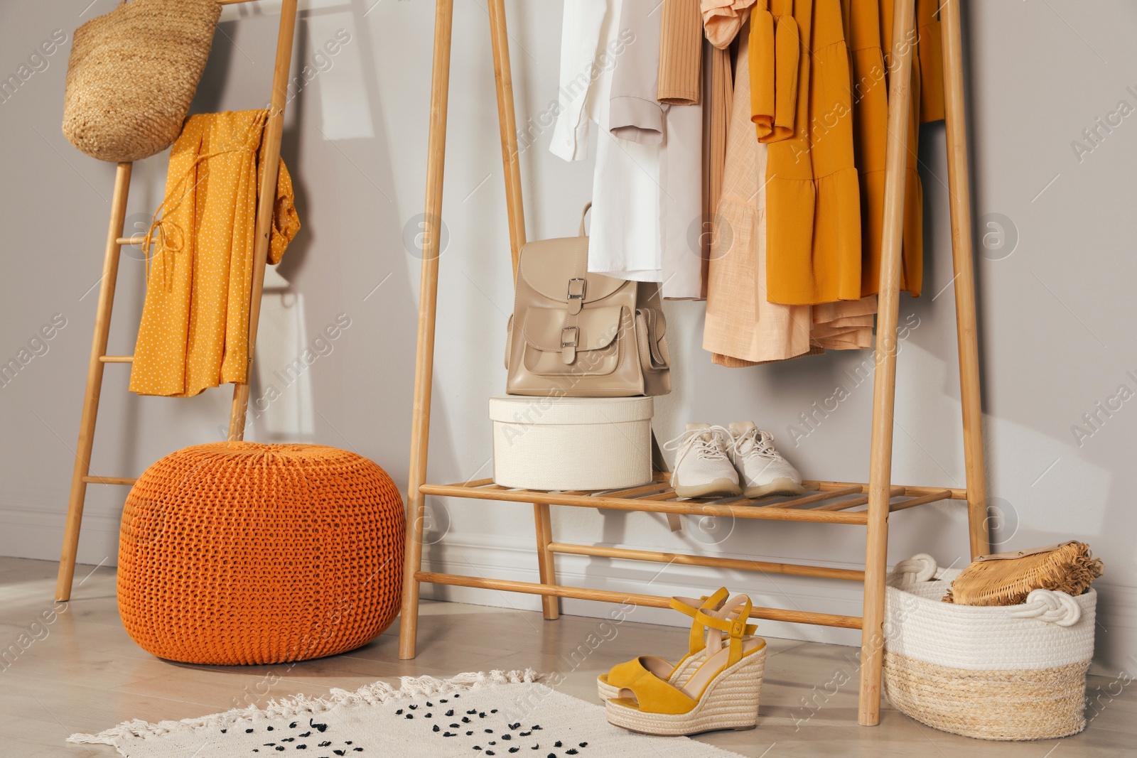 Photo of Modern dressing room interior with stylish clothes, shoes and orange pouf