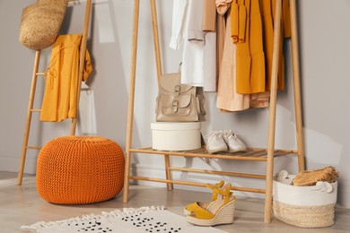 Photo of Modern dressing room interior with stylish clothes, shoes and orange pouf