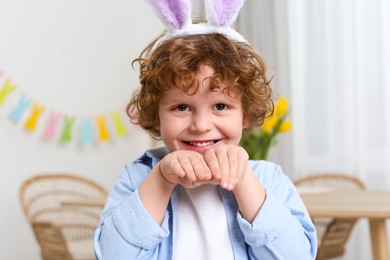 Easter celebration. Happy boy wearing cute bunny ears headband indoors