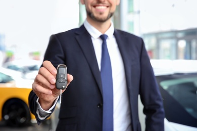 Photo of Businessman with key in dealership. Buying new car