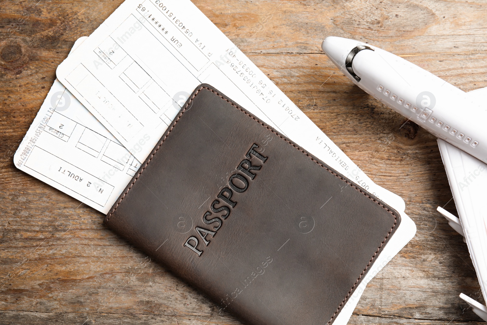 Photo of Passport with tickets and toy plane on wooden table, top view. Travel agency