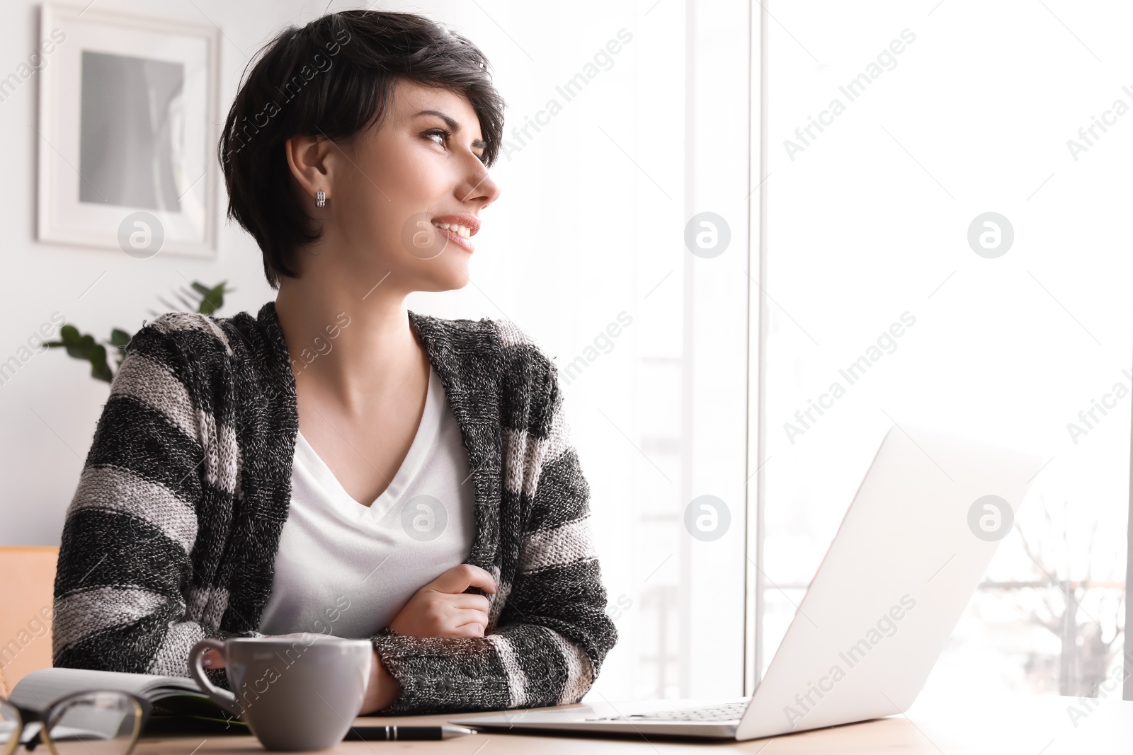 Photo of Young woman working with laptop at desk. Home office