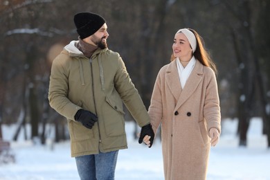 Photo of Beautiful happy couple walking in snowy park on winter day