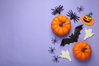 Photo of Flat lay composition with bat, pumpkins, ghosts and spiders on purple background, space for text. Halloween celebration