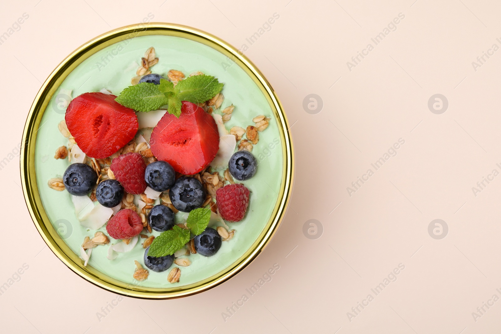 Photo of Tasty matcha smoothie bowl served with berries and oatmeal on beige background, top view with space for text. Healthy breakfast