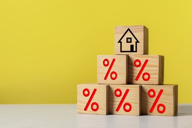 Image of Mortgage rate. Pyramid of wooden cubes with house icon and percent signs on table, space for text