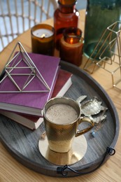 Photo of Wooden tray with decorations, books and hot drink on table