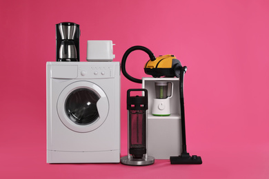 Photo of Set of different home appliances with vacuum cleaner on pink background