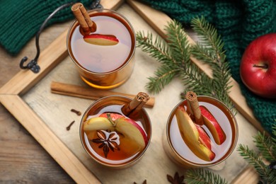 Photo of Hot mulled cider, ingredients and fir branches on wooden table, flat lay