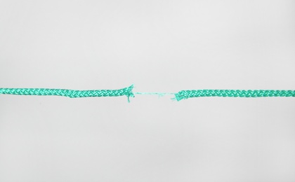 Frayed rope at breaking point on gray background