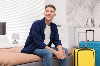Smiling guest relaxing on bed in stylish hotel room