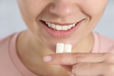 Woman with chewing gums on light background, closeup