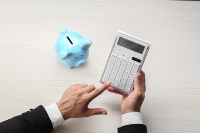 Photo of Businessman calculating at light wooden table, closeup