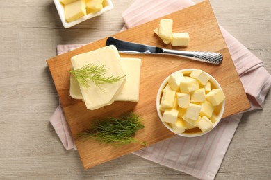 Tasty butter with dill and knife on wooden table, flat lay