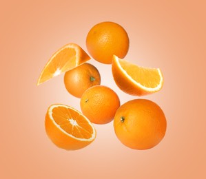 Image of Cut and whole oranges flying on peach background