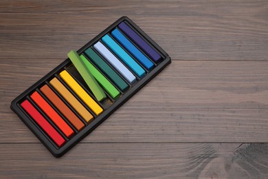 Colorful pastels in tray on wooden table, space for text. Drawing materials