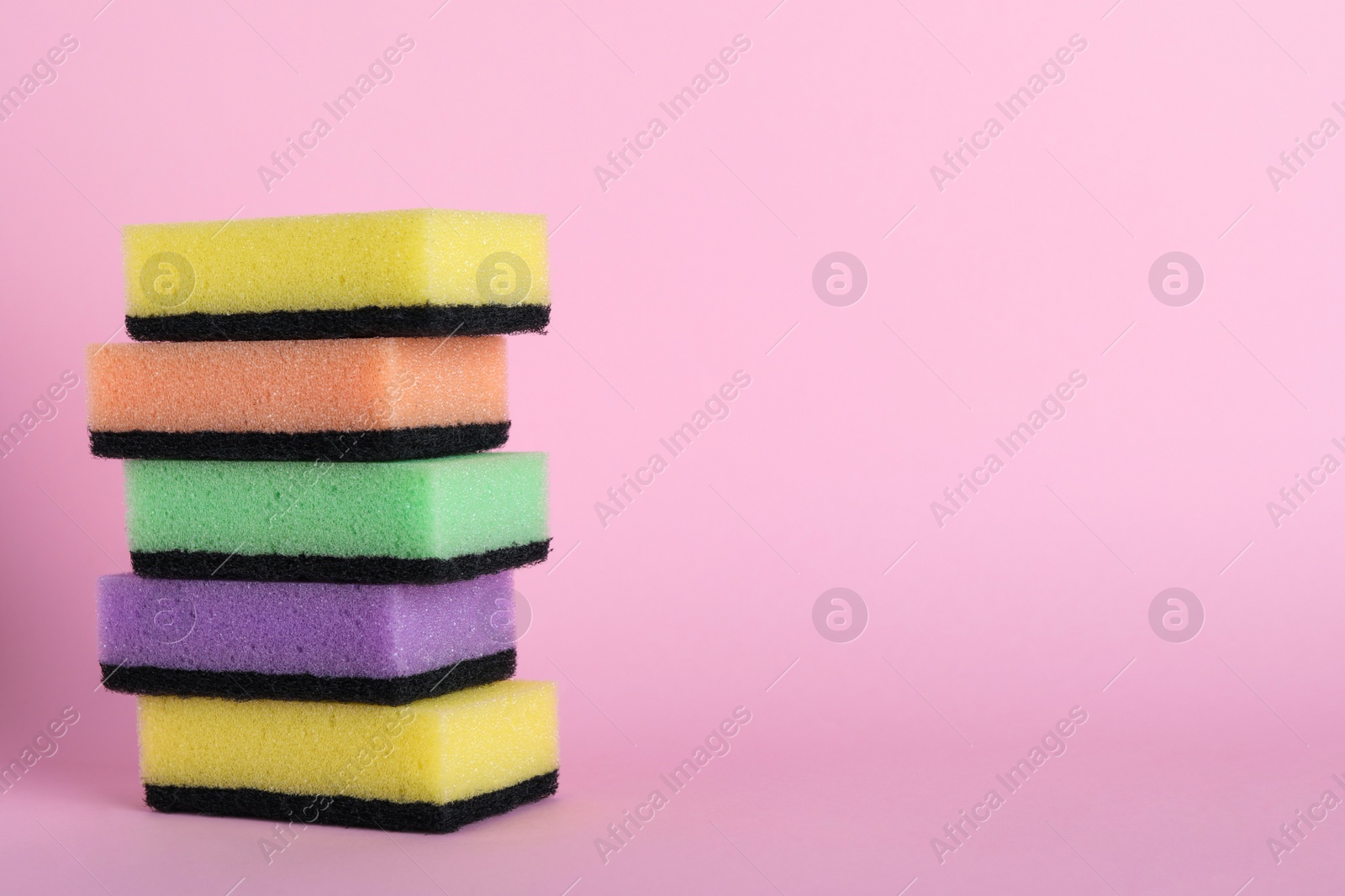 Photo of Stacked sponges on pink background. Space for text