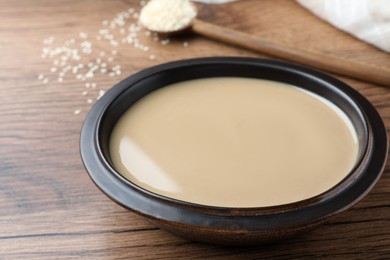 Photo of Tasty sesame paste in bowl on wooden table, closeup