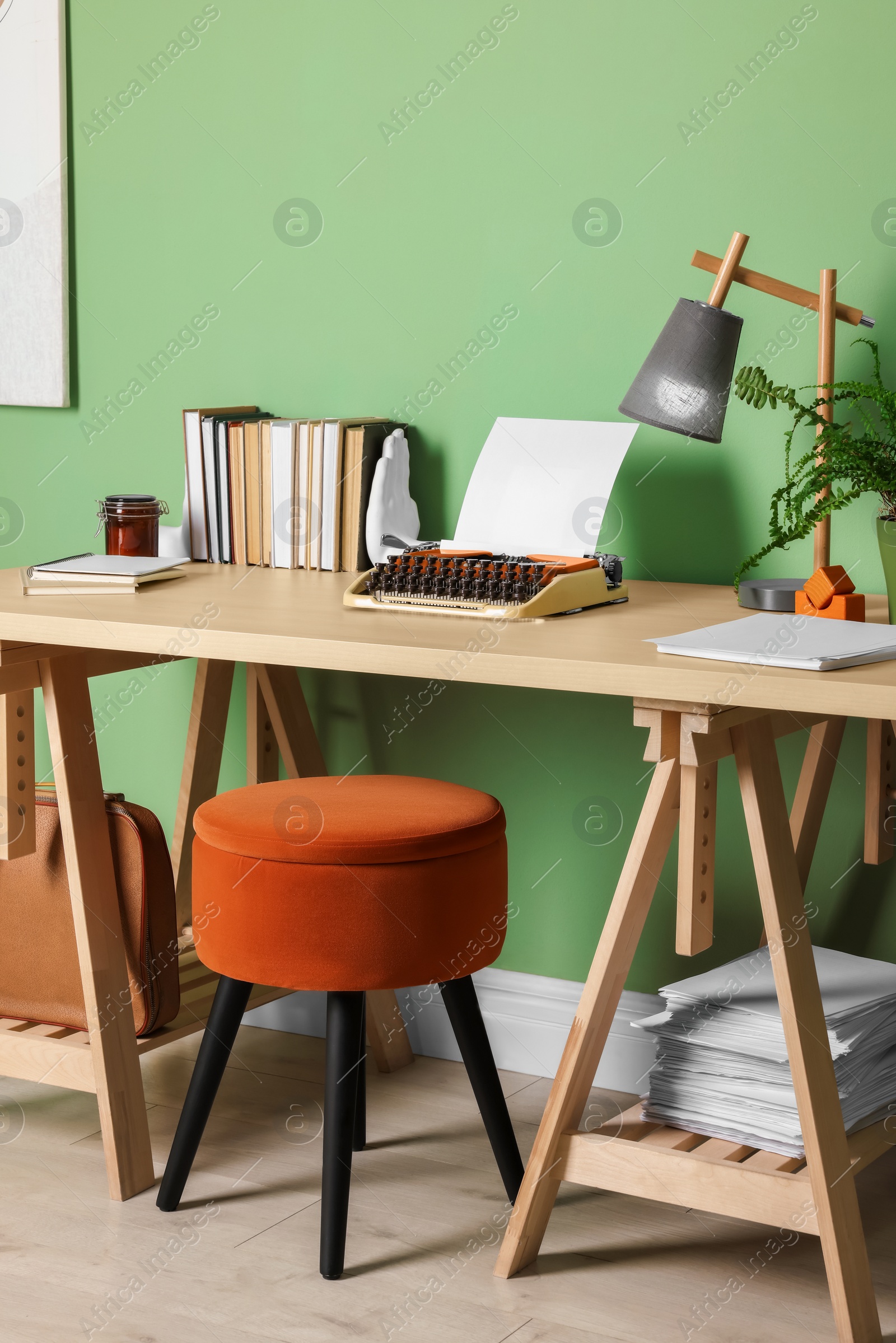 Photo of Writer's workplace with typewriter on wooden desk near pale green wall in room