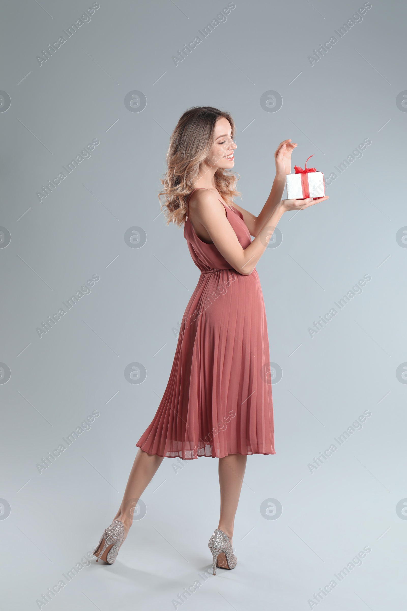 Photo of Beautiful young woman with Christmas present on light grey background